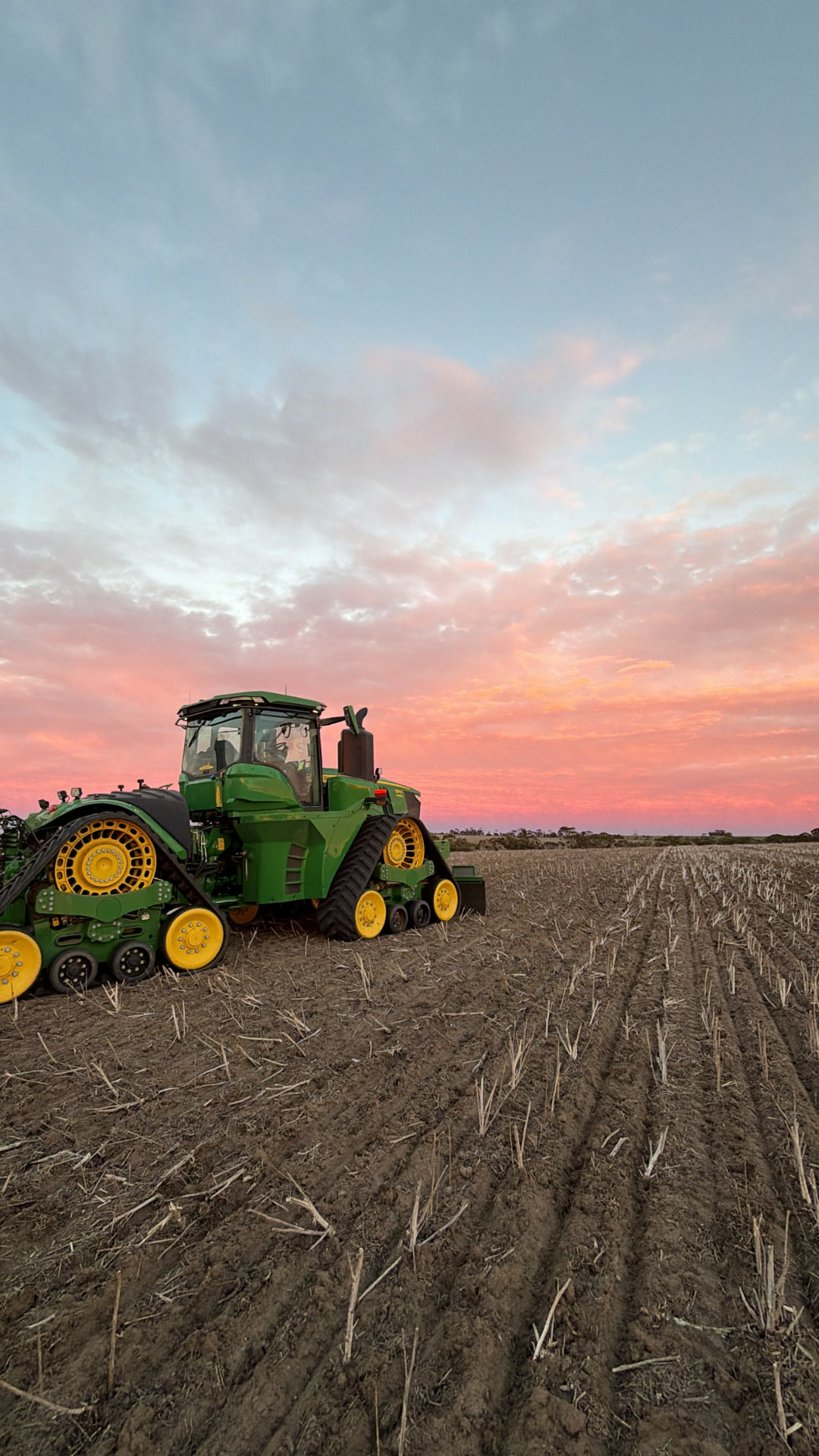 John Deere tracked tractor in an Australian stubble paddock at sunset